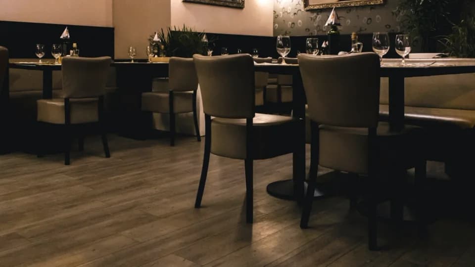 Salle de restaurant aux tables dressées, banquettes et parquet sombre